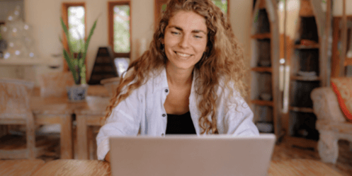 Vrouw kijkt naar een laptop met een vrolijk gezicht